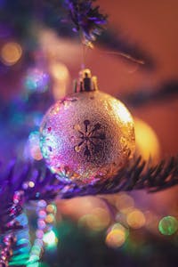 Close-up of a shimmering Christmas ornament with bokeh lights behind, capturing holiday spirit.